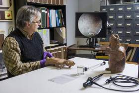 an archaeologist using an endoscope on a ceramic figure