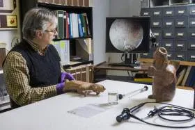 an archaeologist using an endoscope on a ceramic figure